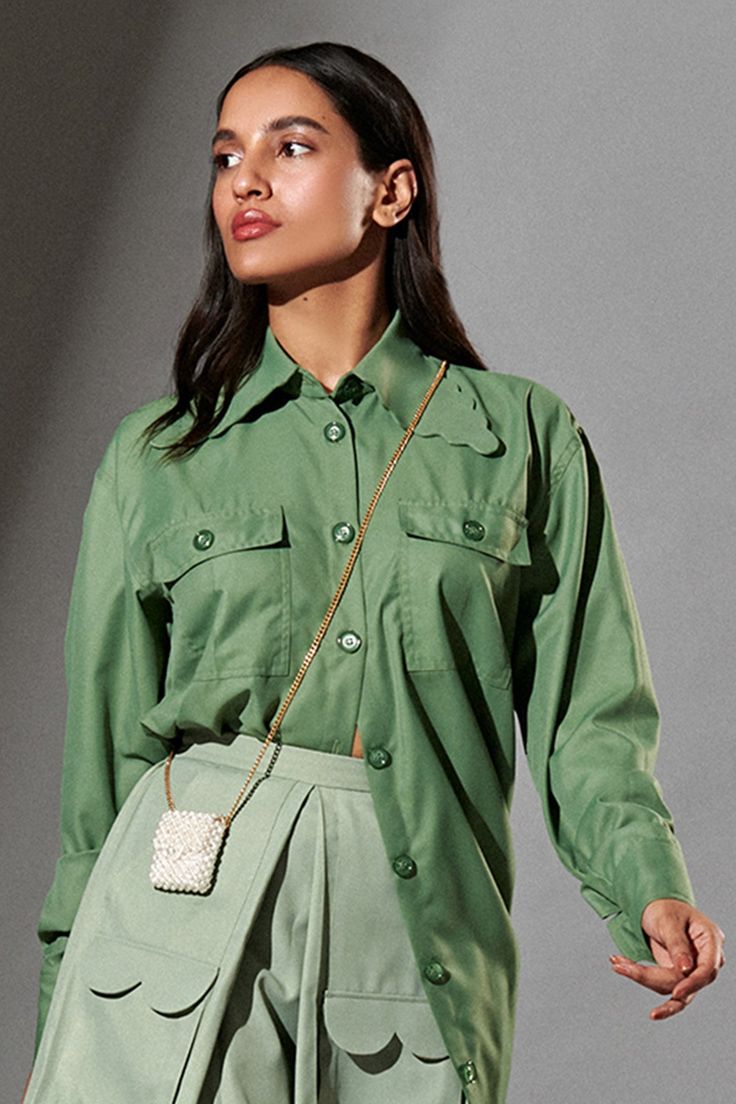 Fern green oversized shirt with scalloped collars patched pockets and front buttons.
Component: 1
Pattern: Plain
Neckline: Collar
Sleeve Type: Cuff Hem Sleeves
Fabric: 80% Polyester, 20% Cotton
Color: Green
Other Details: 
Scalloped hem collar
Oversized silhouette
Front button down
Note: The skirt and sling bag worn by the model is not for sale
Occasion: Party, Work - Aza Fashions Fern Green, Oversized Silhouette, Scalloped Hem, Oversized Shirt, Aza Fashion, Sling Bag, Sleeve Type, Fern, Rain Jacket