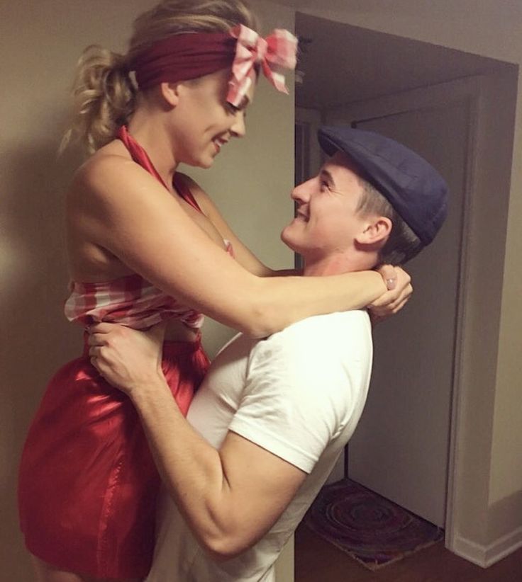 a man is hugging a woman in a red dress and headband while they both look into each other's eyes