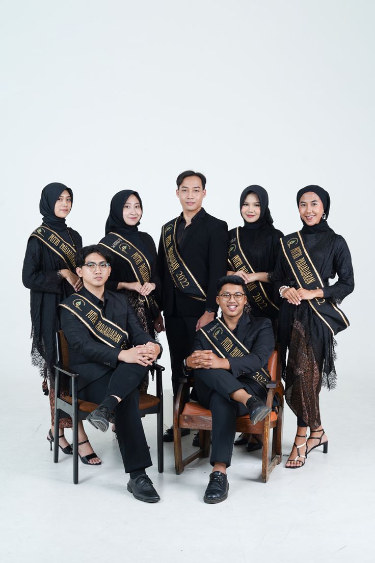 a group of people sitting next to each other in front of a white background wearing black and gold