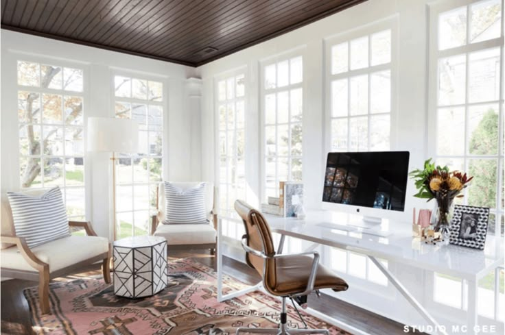 a home office with two chairs and a computer on a desk in front of large windows