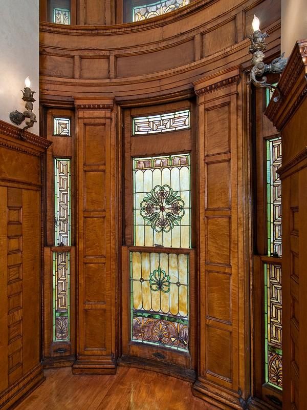 a room with stained glass windows and wooden doors on the walls, along with wood flooring