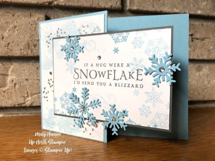 a card with snowflakes on it sitting on a table next to a brick wall