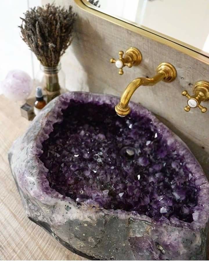 a bathroom sink that has some kind of purple rock in the middle of it and gold faucet