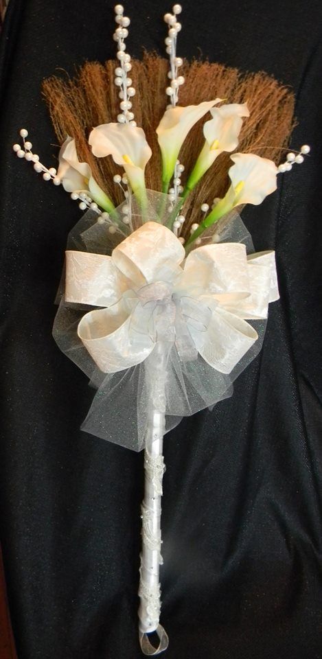 a bouquet with white flowers and brown feathers on top of a black cloth covered table