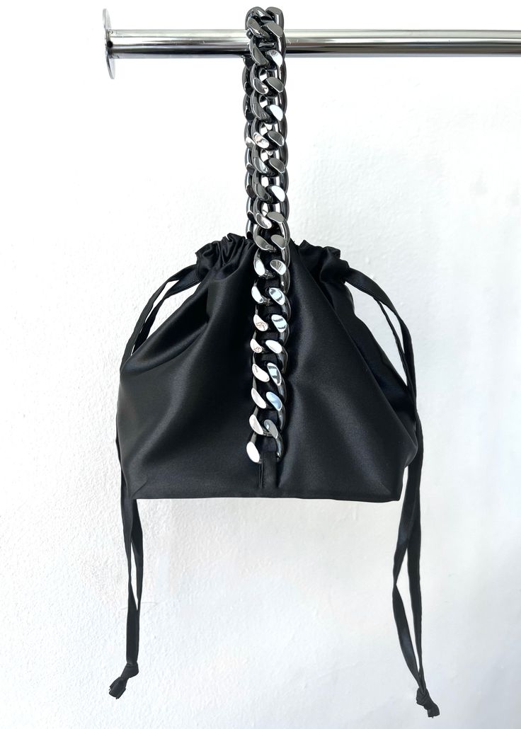 Our smooth satin drawstring bag gathers at the top from a square structured base, and is handled by gun metal hardware that creates and elegant yet fierce pouch bag. Satin shell, satin lining, gun metal hardware. Polyester 100%. Drawstring closure. 6"x 6" base Made in USA. One Size. Need help with sizing? Size Guide Silver Bucket Bag With Dust Bag For Formal Occasions, Elegant Silver Bucket Bag For Evening, Elegant Pouch Bucket Bag With Silver-tone Hardware, Elegant Evening Pouch Bucket Bag, Chic Evening Bucket Pouch, Elegant Evening Bucket Bag In Pouch Style, Elegant Evening Bucket Bag Pouch, Elegant Evening Bucket Bag With Silver-tone Hardware, Party Shoulder Bag With Gunmetal Hardware And Top Handle