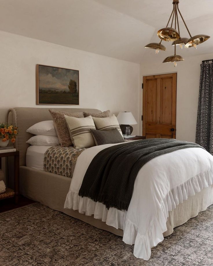 a bedroom with a large bed and chandelier hanging from it's ceiling