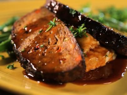 two pieces of meat covered in sauce and garnished with parsley on a yellow plate