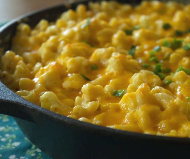 a skillet filled with macaroni and cheese on top of a blue plate