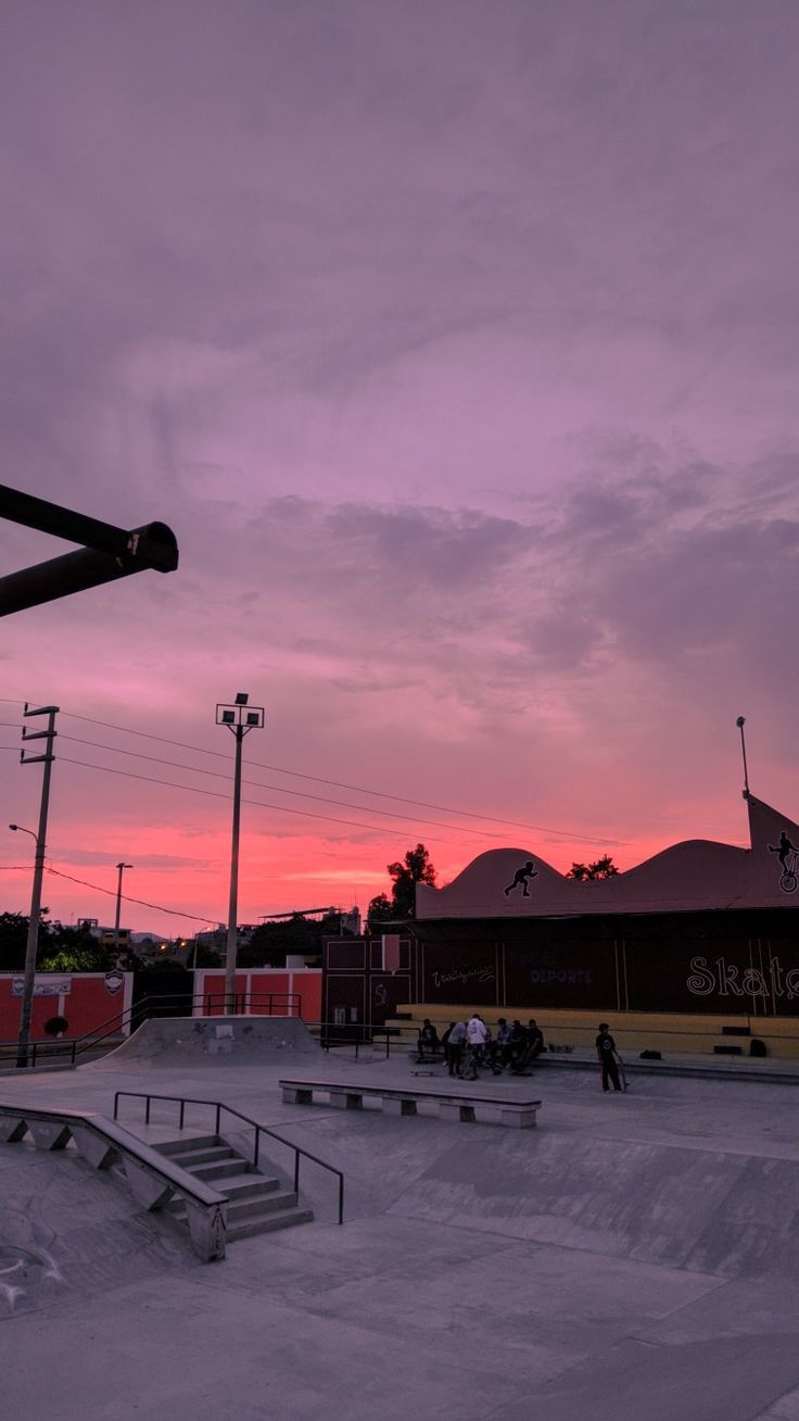 a skateboard park with people skating at sunset