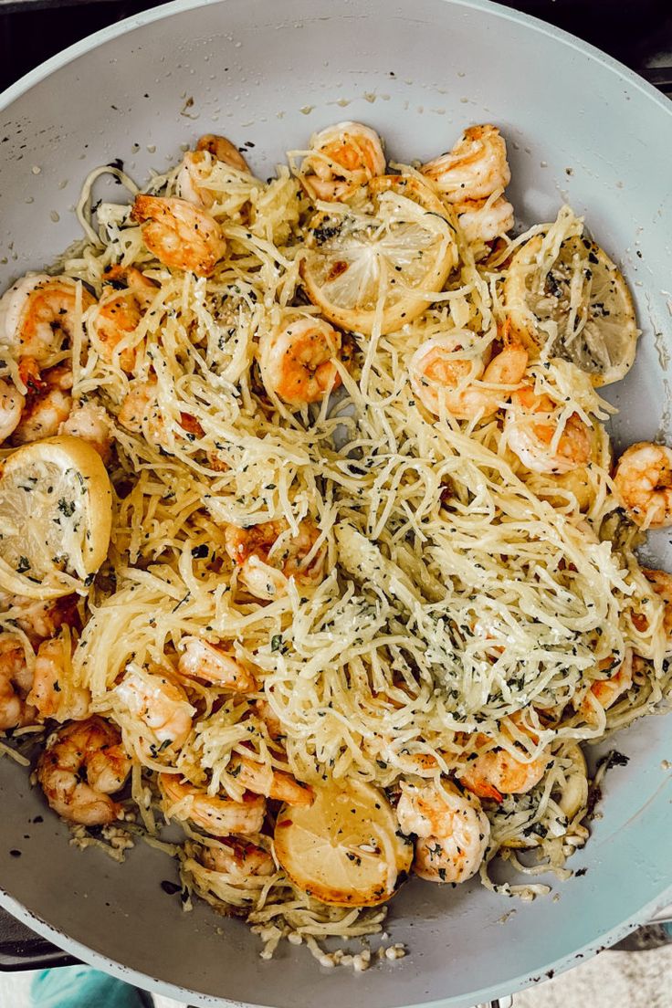 a pan filled with pasta and shrimp on top of a stove