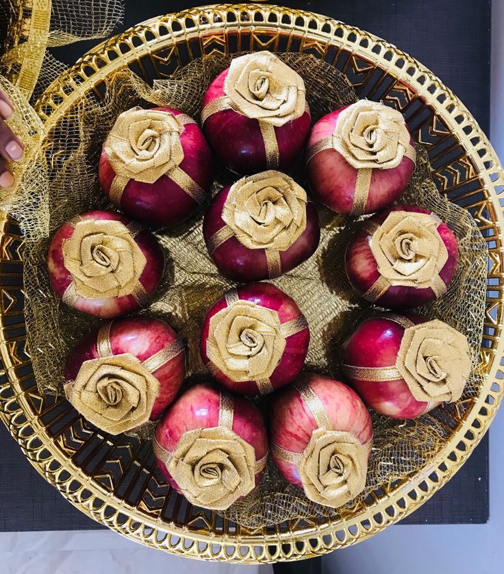 there are onions in the bowl with gold ribbon around them and roses on each side