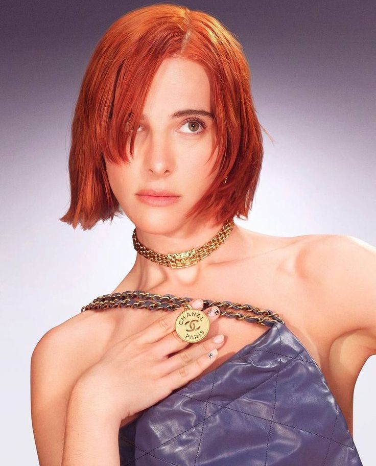 a woman with red hair wearing a blue dress and holding a gold coin in her hand