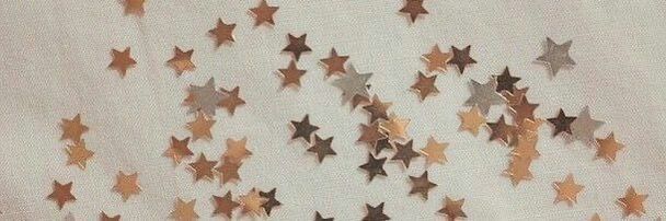 many small stars are hanging on the wall in front of a white curtain with gold trim