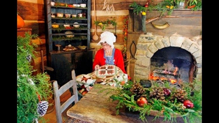 a woman sitting at a table in front of a fire place with christmas decorations on it