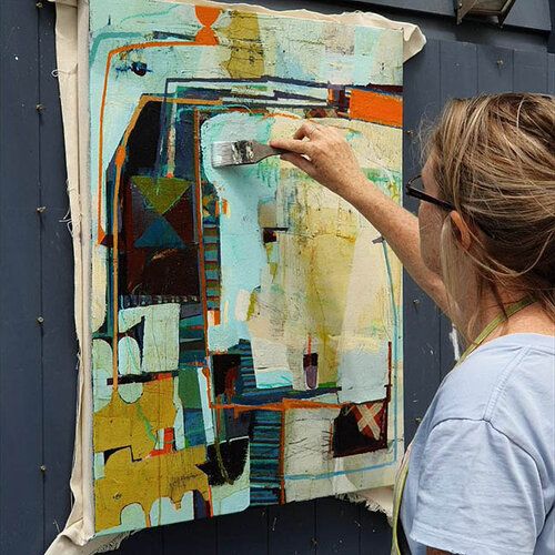 a woman is painting on the side of a building with blue and yellow paint,