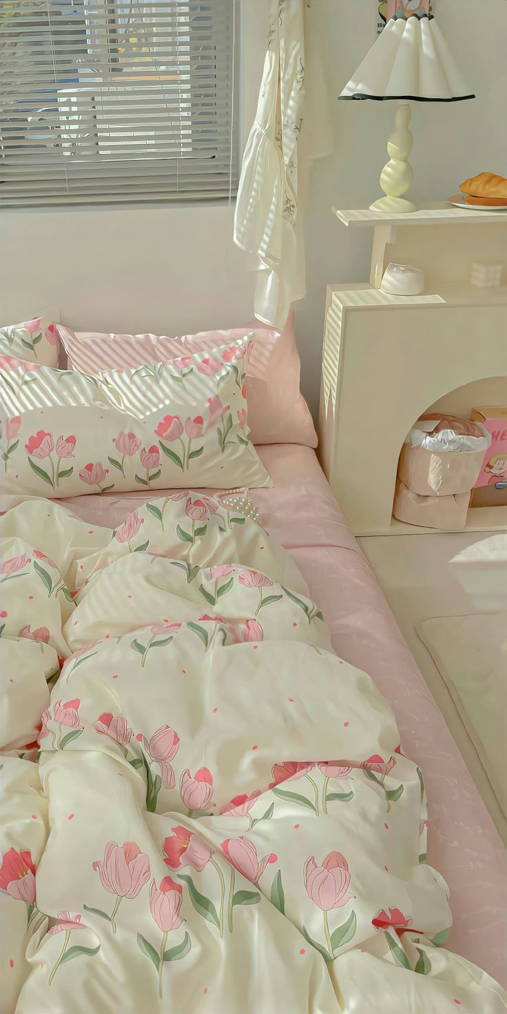 a bed with pink flowers on it in a bedroom next to a dresser and window