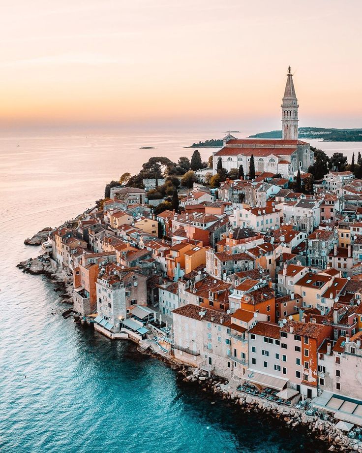 an aerial view of the old town of rovinik in croatia at sunset with water and buildings