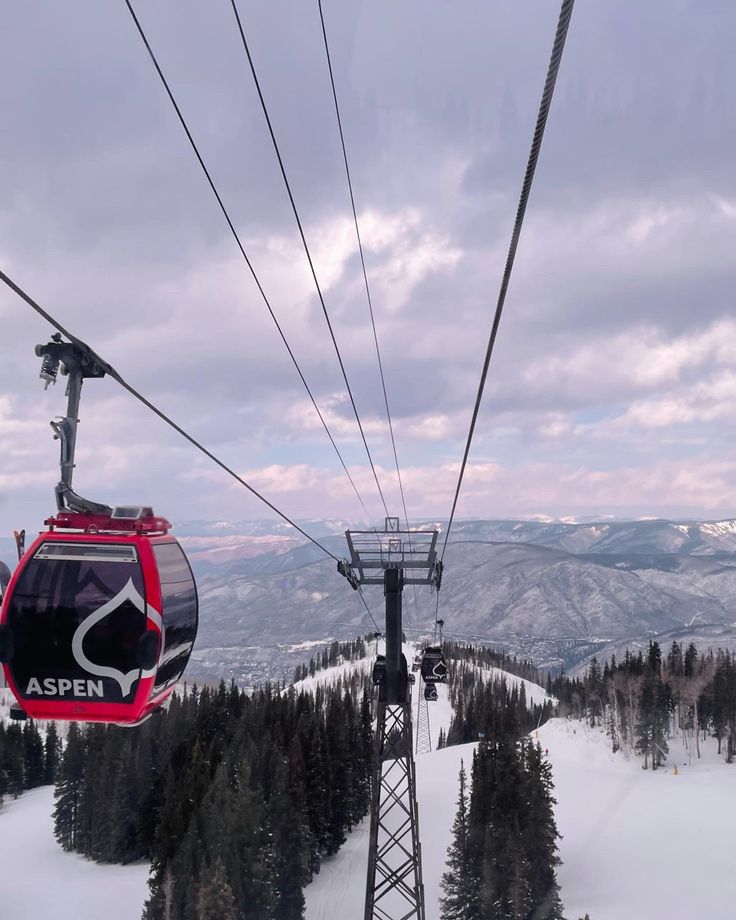 a ski lift with two people on it going up the mountain in front of snow covered trees