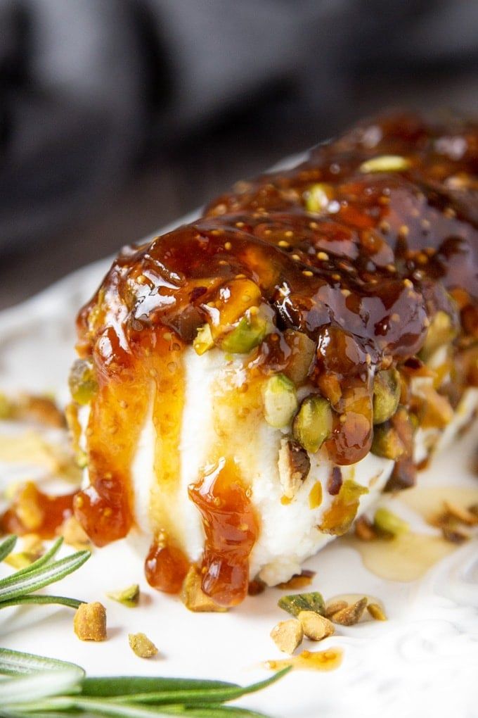 a close up of a piece of food on a plate with sauce and nuts around it