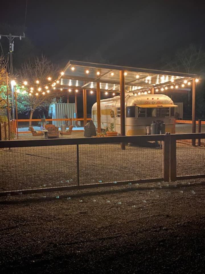 an rv is parked in front of a fence with lights on it at night time