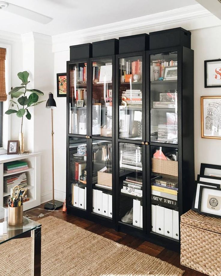 a black bookcase filled with lots of books in a living room next to a window