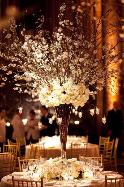 an elegant centerpiece with white flowers and candles is the focal point for this wedding reception