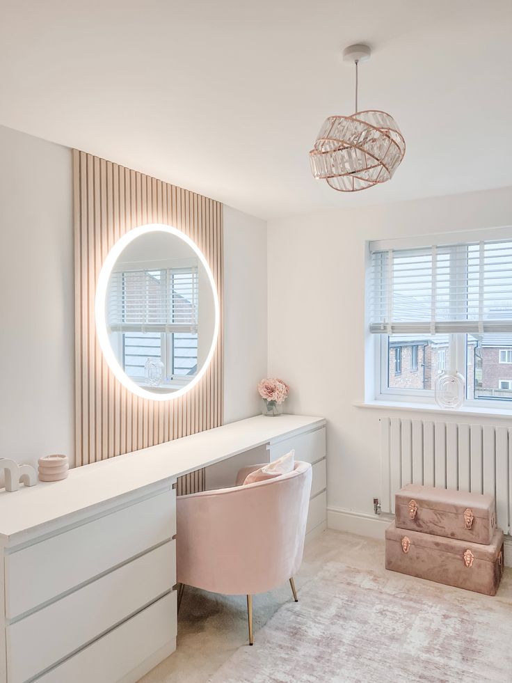 a white room with a vanity, chair and round mirror on it's wall