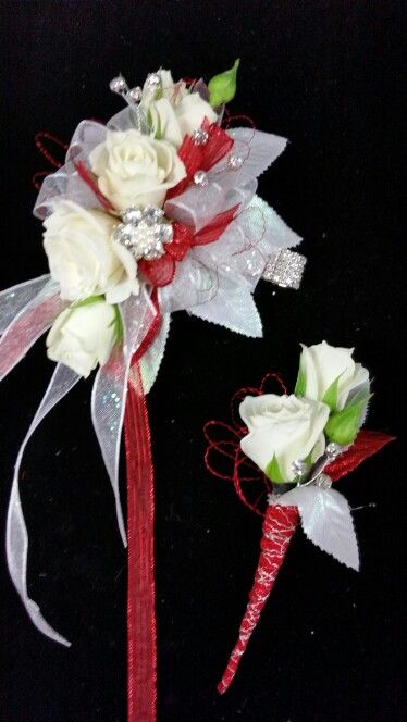 two white roses with red ribbons on black background