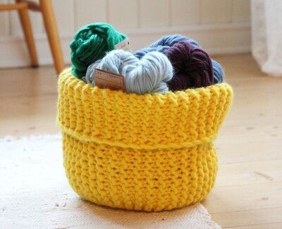 a basket filled with yarn sitting on top of a wooden floor