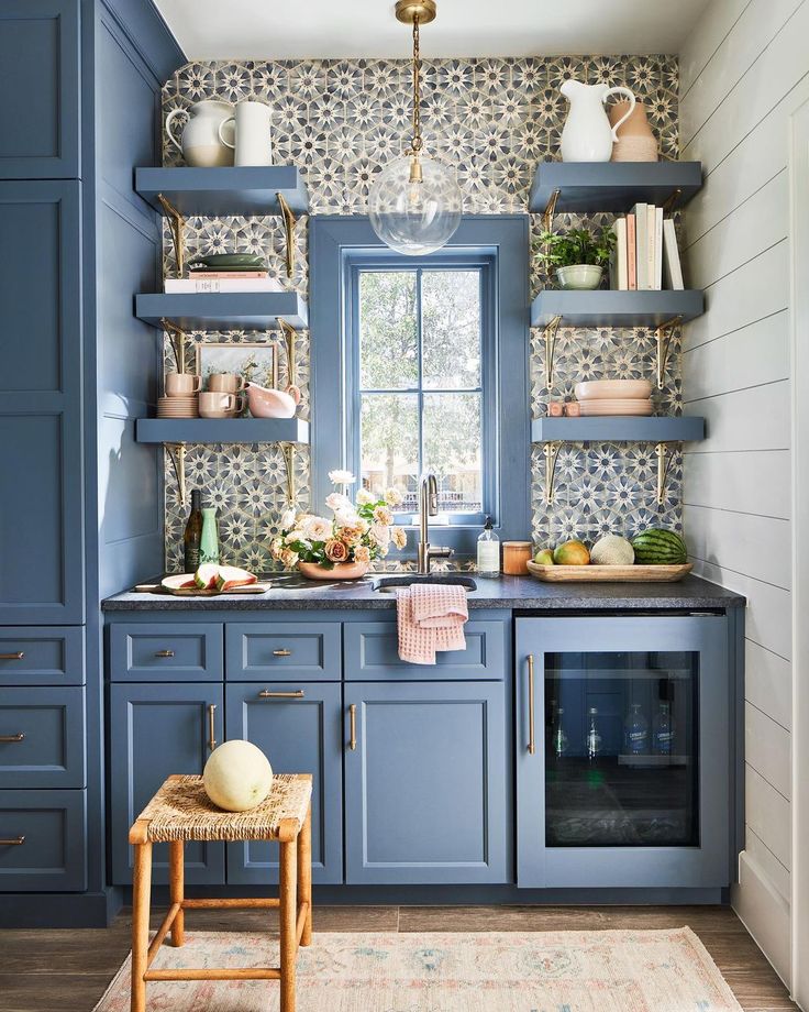 a kitchen with blue cabinets and shelves filled with dishes