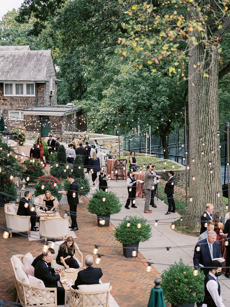 a group of people sitting around tables in the middle of a courtyard with lights on them