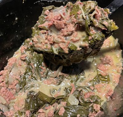 the food is being cooked in the pot with it's ladle full of meat and vegetables