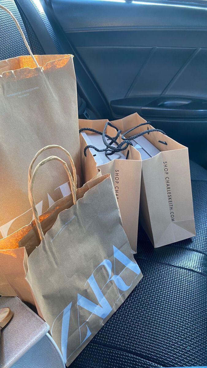 two brown bags sitting on the back seat of a car, next to some shoes