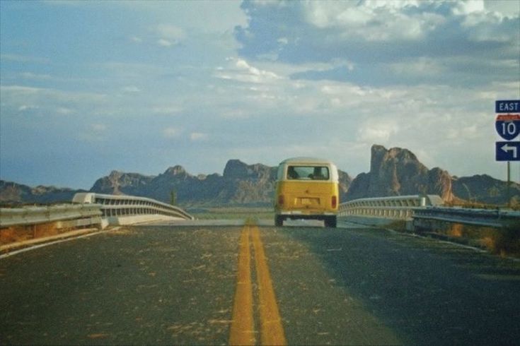 a yellow bus driving down a road next to mountains and a sign that says east 10