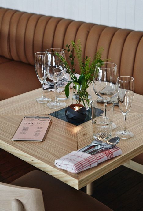 a wooden table topped with lots of wine glasses and place settings on top of it