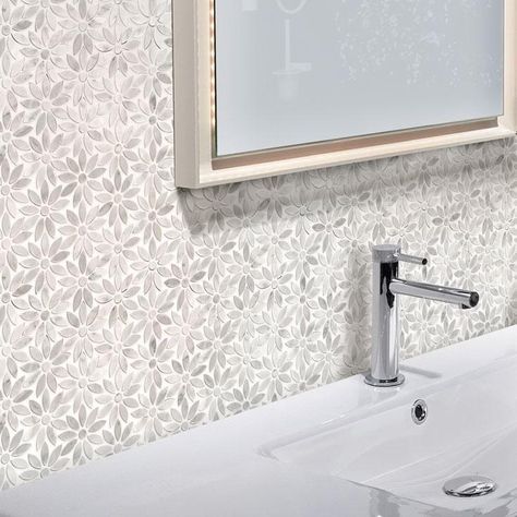 a bathroom sink sitting under a mirror in front of a wall papered with leaves