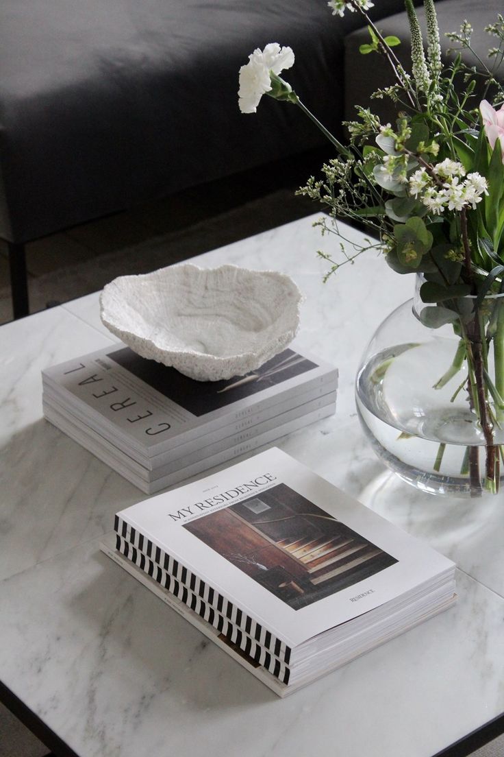 two books and a vase with flowers on a table