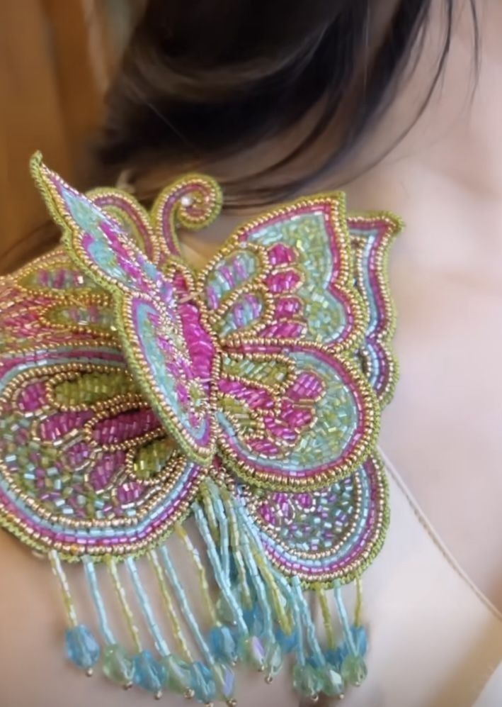 the back of a woman's bra with beaded butterfly design on her chest