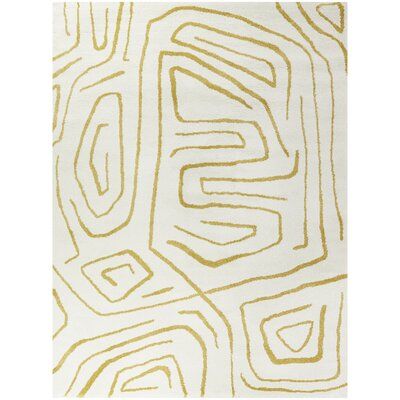 a white and gold rug with an abstract design on the bottom, in front of a white background