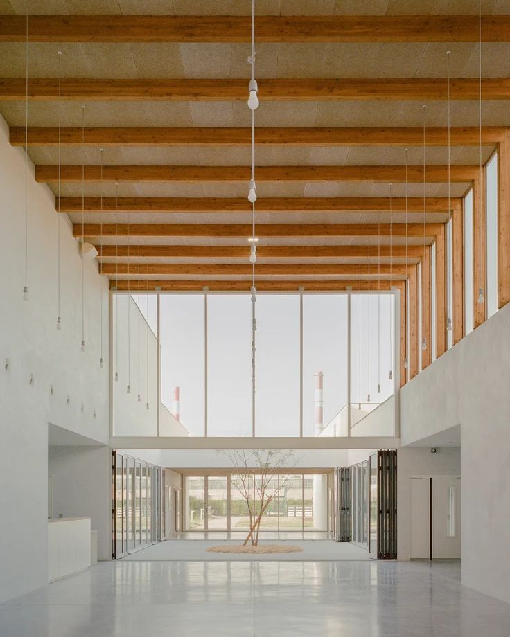 an empty room with large windows and wooden ceiling