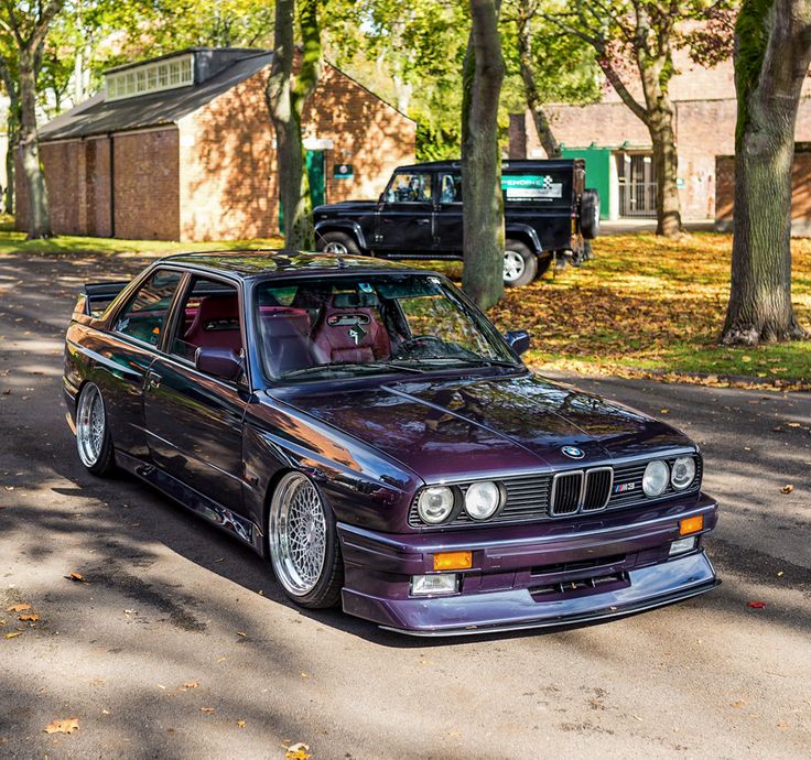 a purple car parked on the side of a road next to a tree filled street