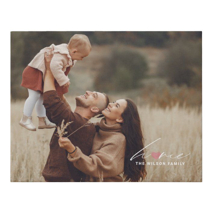 a man holding a baby up to his face while standing next to a woman in a field