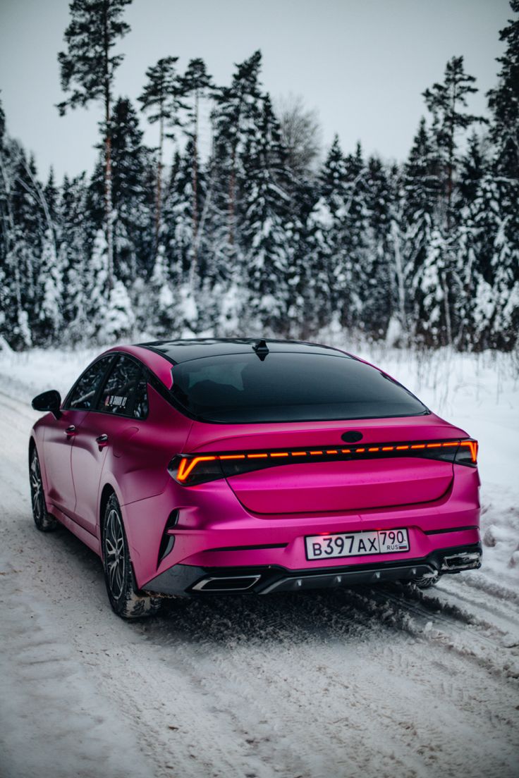 a pink car driving down a snow covered road