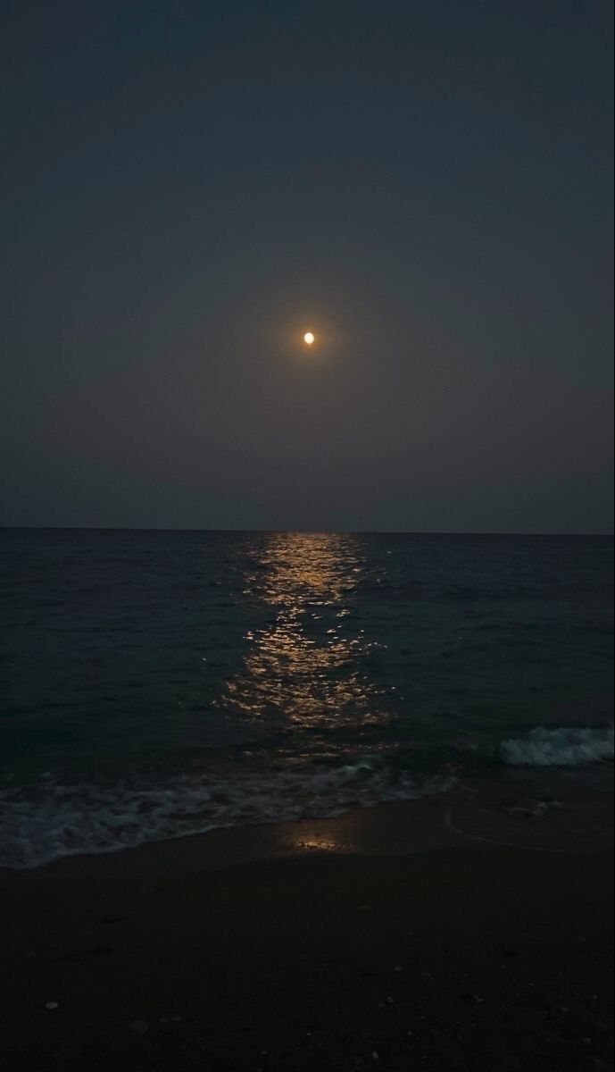 the moon is shining over the ocean at night