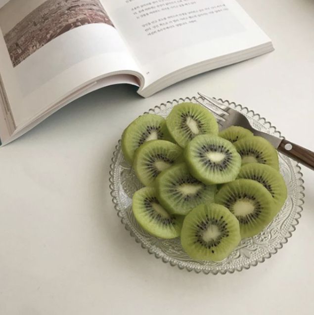 kiwi slices on a glass plate next to an open book