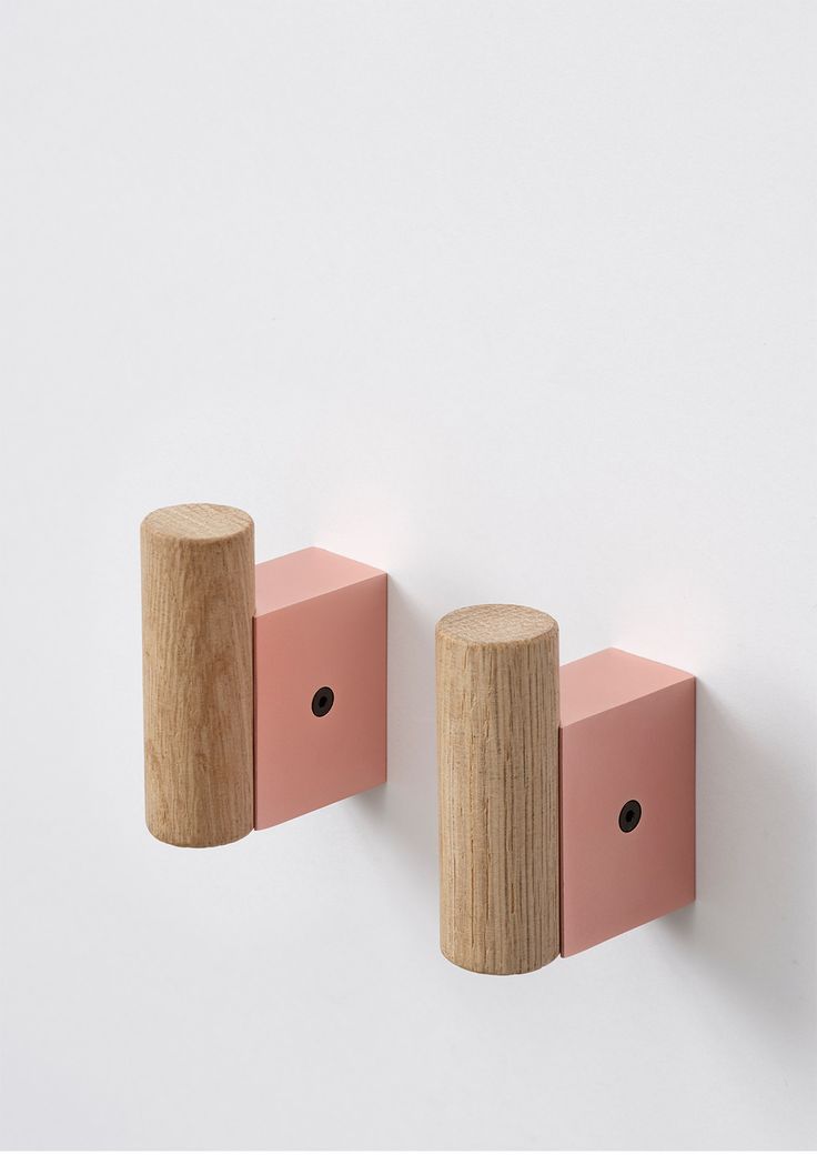 two wooden pegs are attached to the wall, one is pink and the other is brown