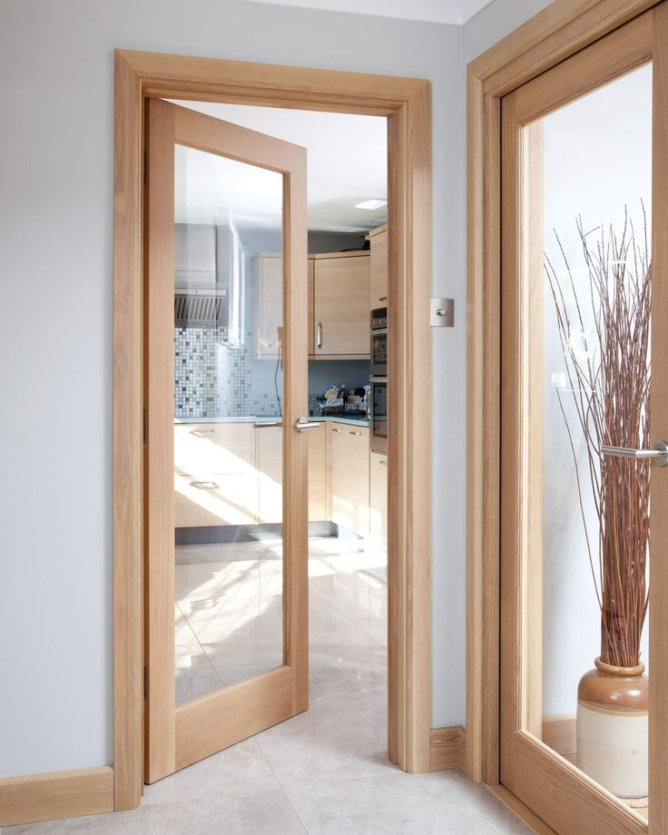 an open door leading to a kitchen and living room with wood furniture in the background