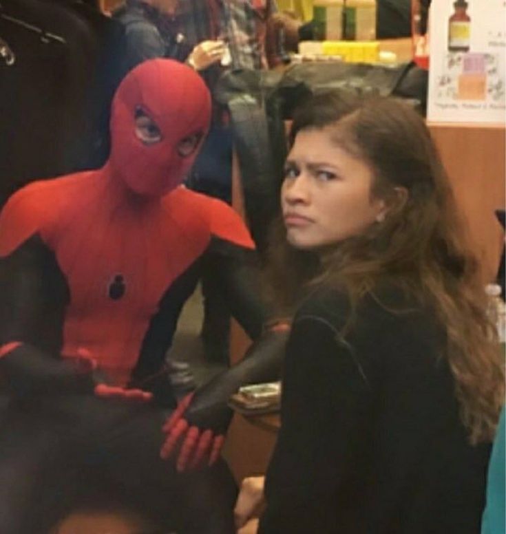 a woman sitting next to a man in a spiderman costume at a store counter