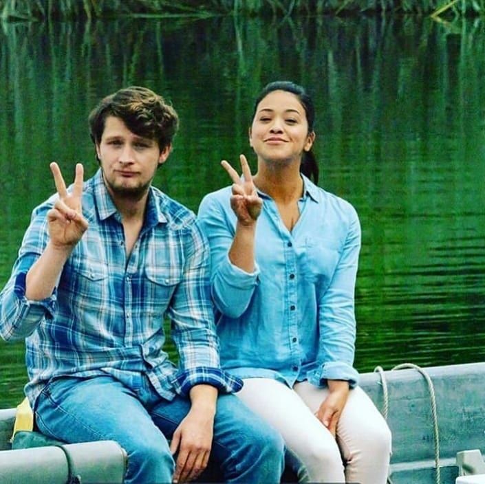 a man and woman sitting on a boat giving the peace sign