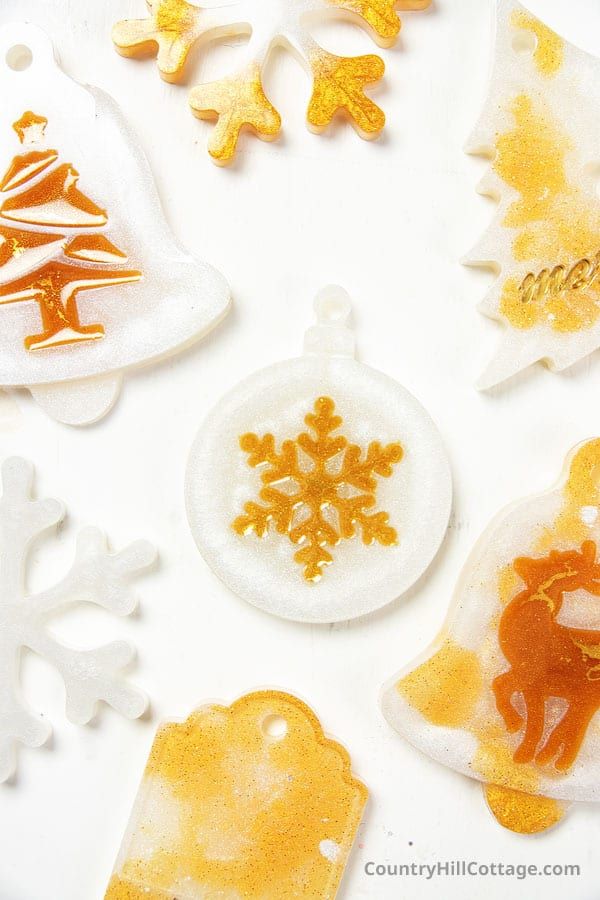 christmas ornaments are shown on a white surface with snowflakes and trees in the background